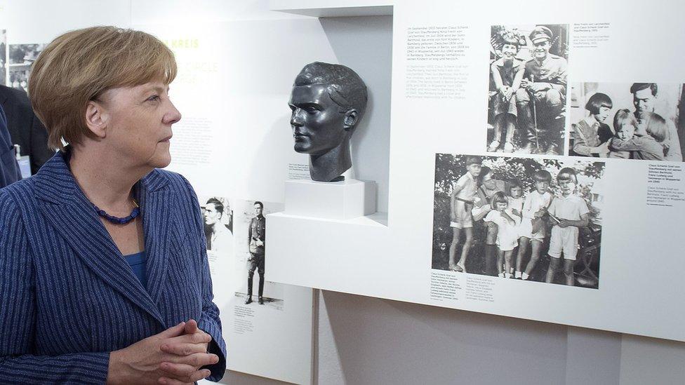 German Chancellor Angela Merkel stands next to a photo of anti-Nazi conspirator Claus von Stauffenberg while looking at exhibits at the newly-expanded museum of the German Resistance Memorial Center