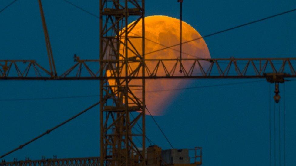 The moon standing in a partial lunar eclipse can be seen behind a construction crane on August 7, 2017 in Gilching, southern Germany.