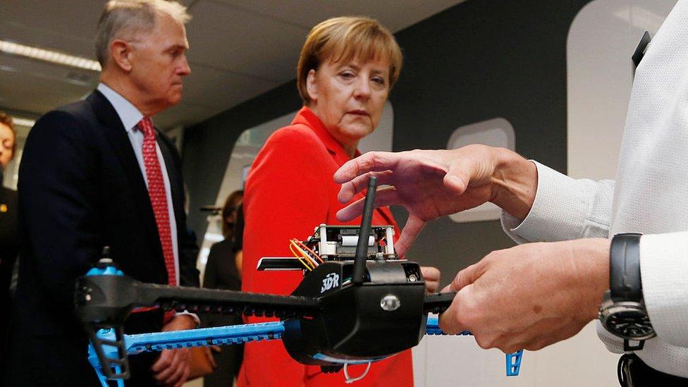 Germany's Chancellor Angela Merkel looks at a drone prototype whose electronics are designed to withstand cyber attack during Merkel's visit to the Future Logistics Living Lab on November 17, 2014 in Sydney, Australia.