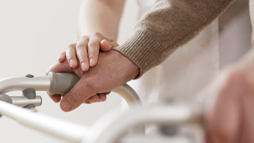 Elderly person and carer with walking frame