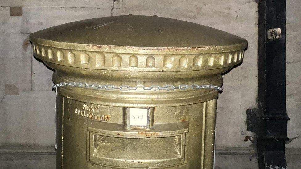 A missing crocheted topper on a gold postbox in Bedford