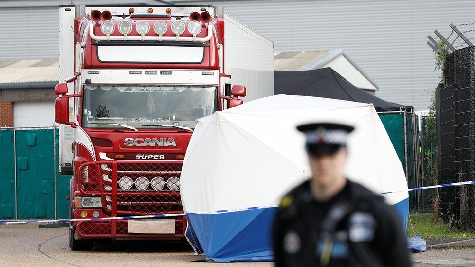 Police officer and forensic tent near lorry