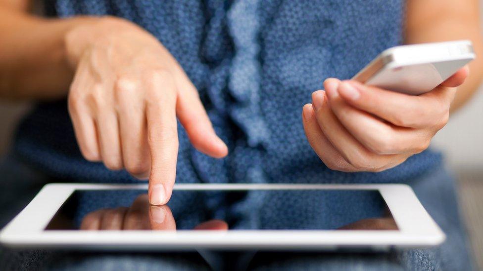 A woman holding a phone and tablet