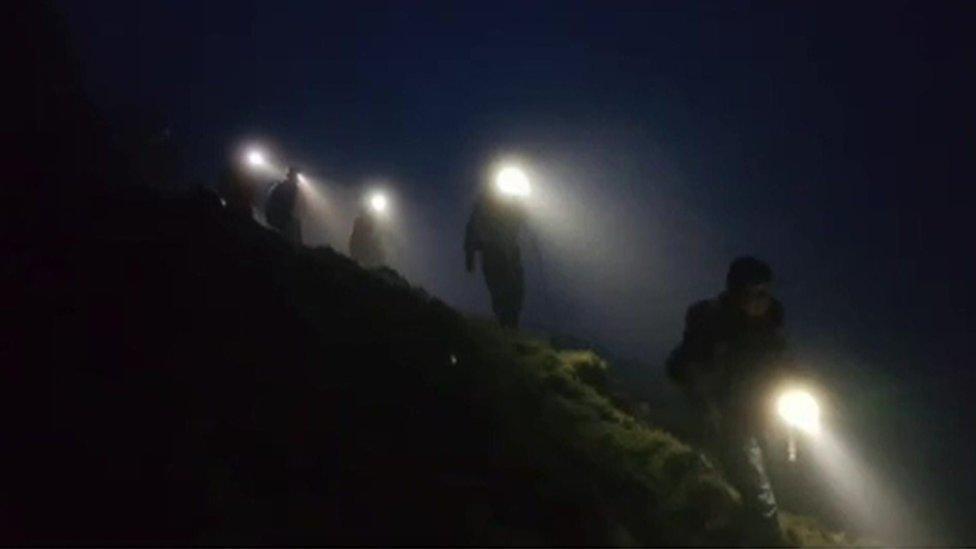 Team on mission to help two men, rescuers in dark wearing head torches