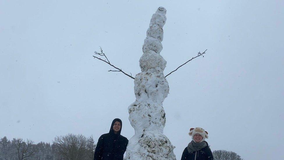 snowman towers over a man and a woman