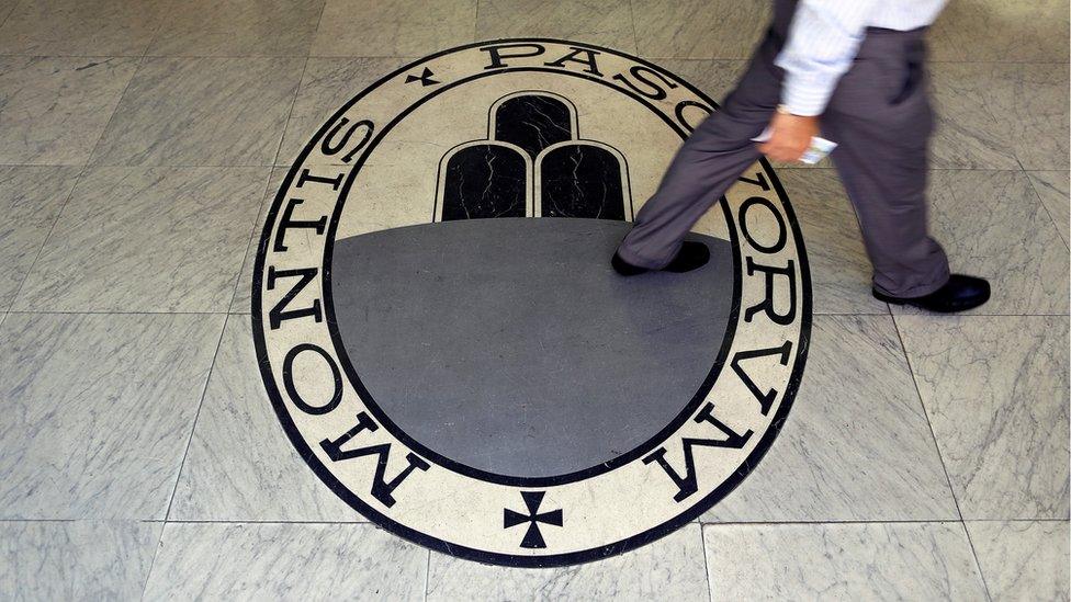 A man walks on a logo of the Monte Dei Paschi Di Siena bank in Rome