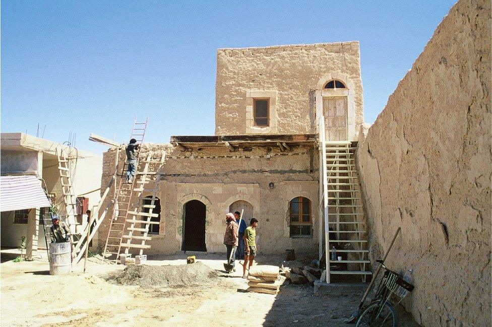 Men on ladders repair a tower in the complex