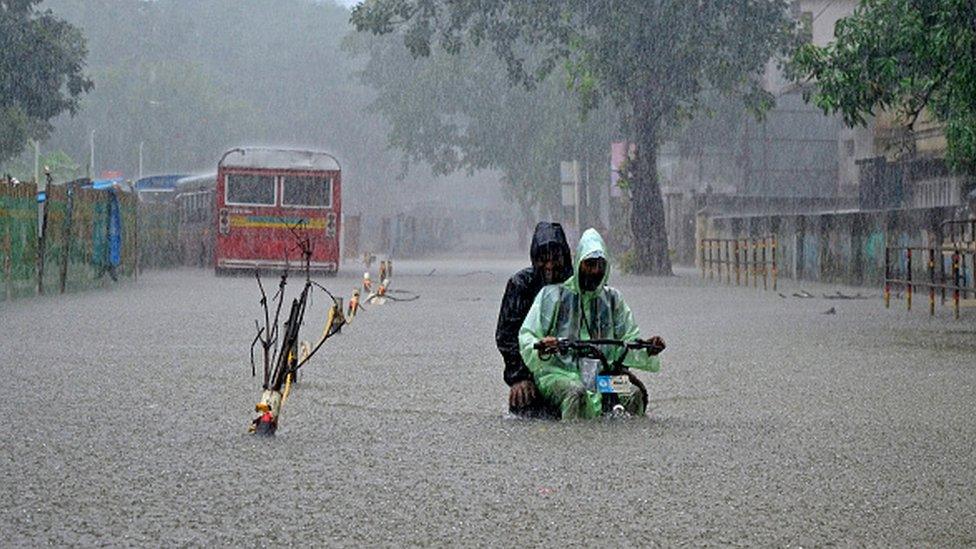 A delivery boy with a electric cycle wades through a flooded street due to heavy rainfall in Mumbai, India, 05 July, 2022.