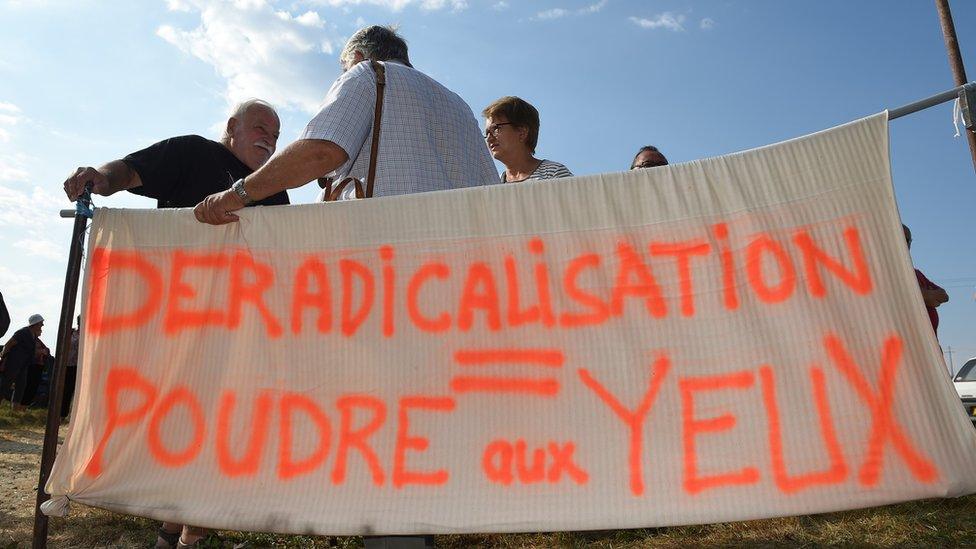 Banner reading: "De-radicalisation = smoke and mirrors"