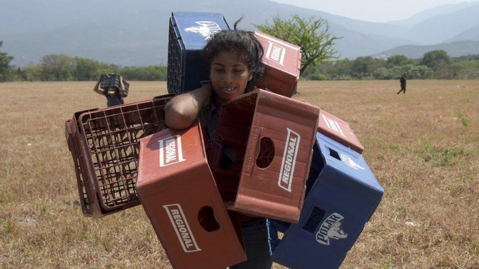 Venezuelan Dayana Pirela carries empty soda and beer crates to sell