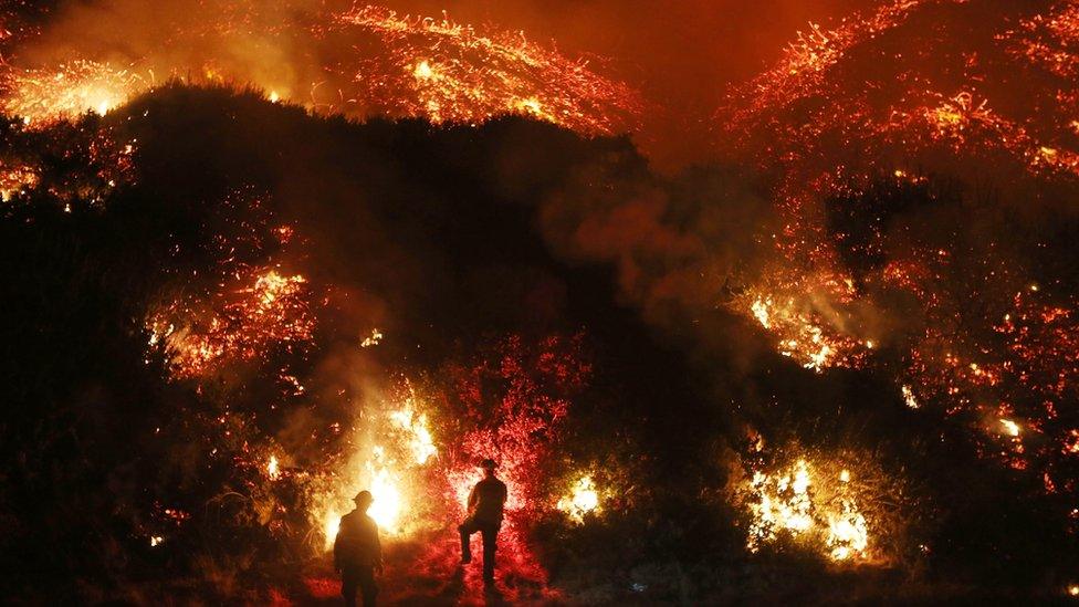 Image shows firefighters monitoring a section of the Thomas Fire along the 101 freeway on December 7, 2017 north of Ventura, California.