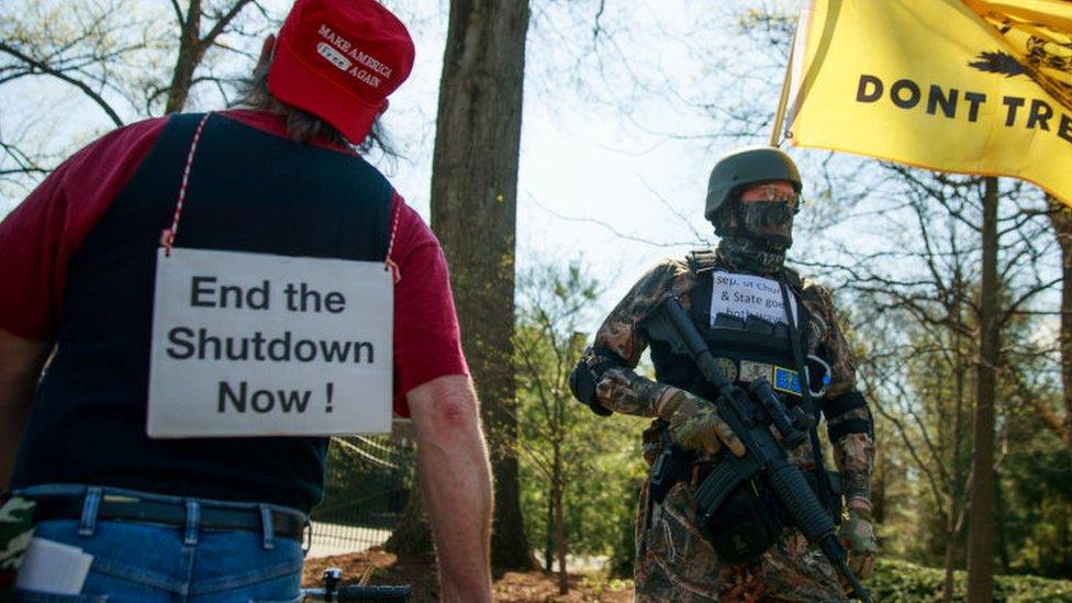 A protester open carries an AR style black military type rifle during a demonstration against Indiana's stay home orders