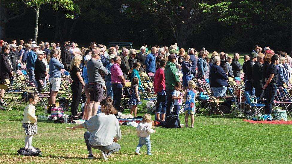 People standing watching a big screen in Guernsey's Saumarez Park showing the state funeral of Queen Elizabeth II