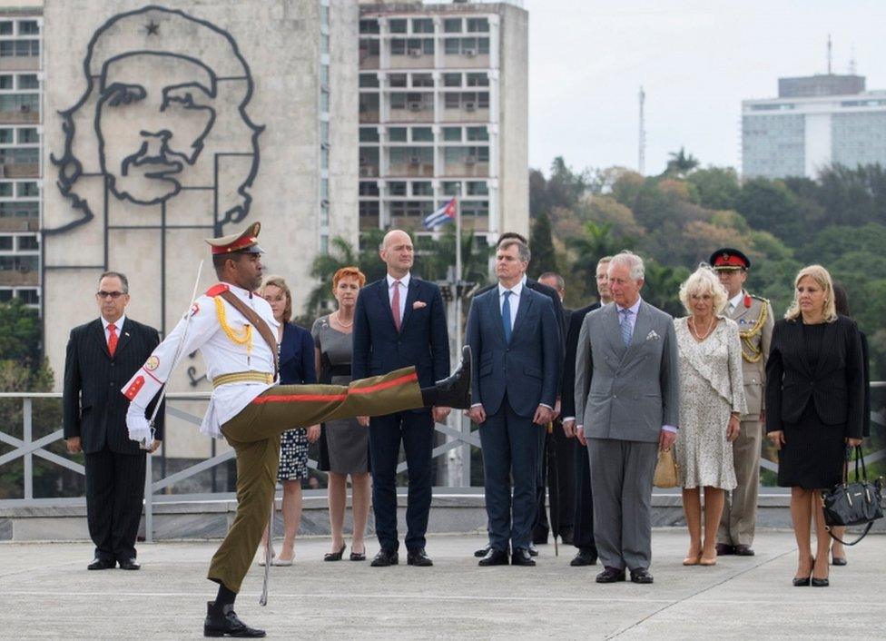 Prince Charles and Camilla stand and watch the wreath layering ceremony