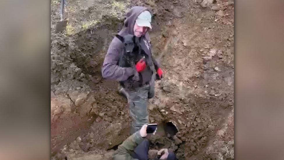 Man holding dog freed from underground pipe