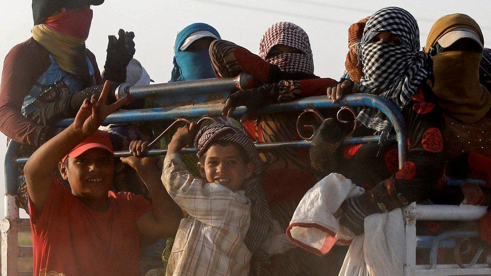 Two young boys wave as residents displaced by fighting between Syrian Democratic Forces and Islamic State militants ride on a truck near Raqqa