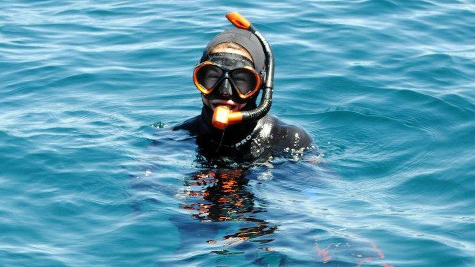 A woman in scuba gear floats in the water