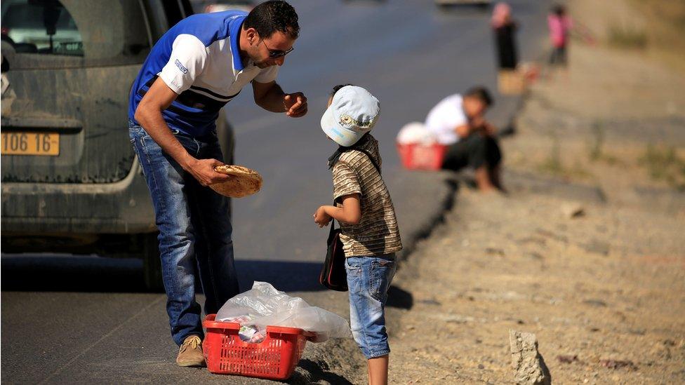 A seller of traditional bread listens to a customer (L) on the edges of a highway during Ramadan on the outskirts of Algiers, Algeria - Monday 13 June 2016