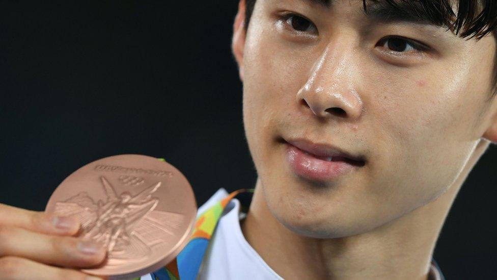 South Korea's Kim Sohui poses with his bronze medal after the men's taekwondo