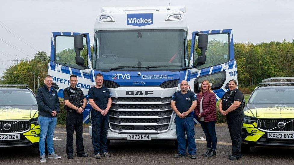 Large blue and white lorry cab with "Julie May" on the front and six people standing in front of it