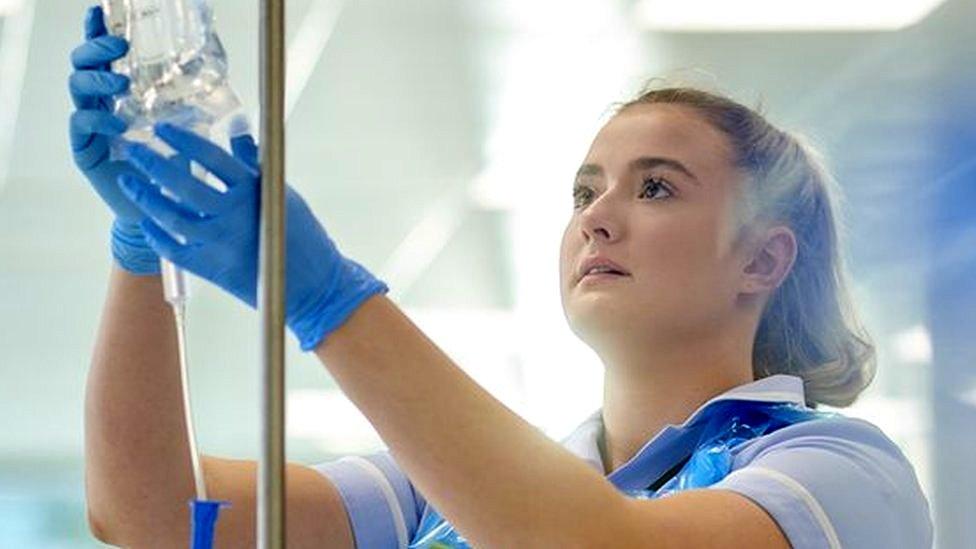 A nurse inspects a drip