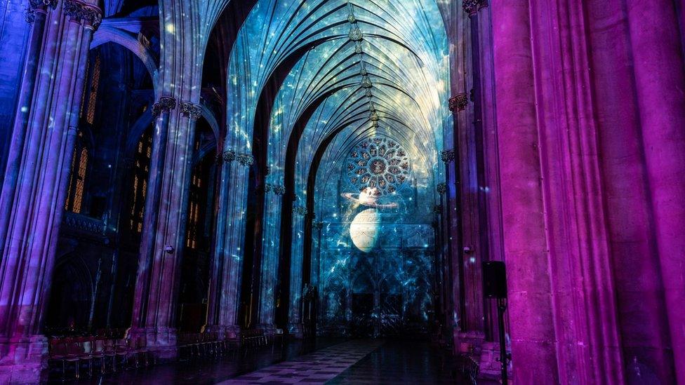 A photo of planets and stars being projected onto the cathedral walls