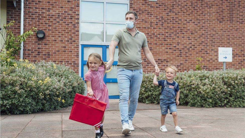 Stock photo man with children at school gate wearing mask