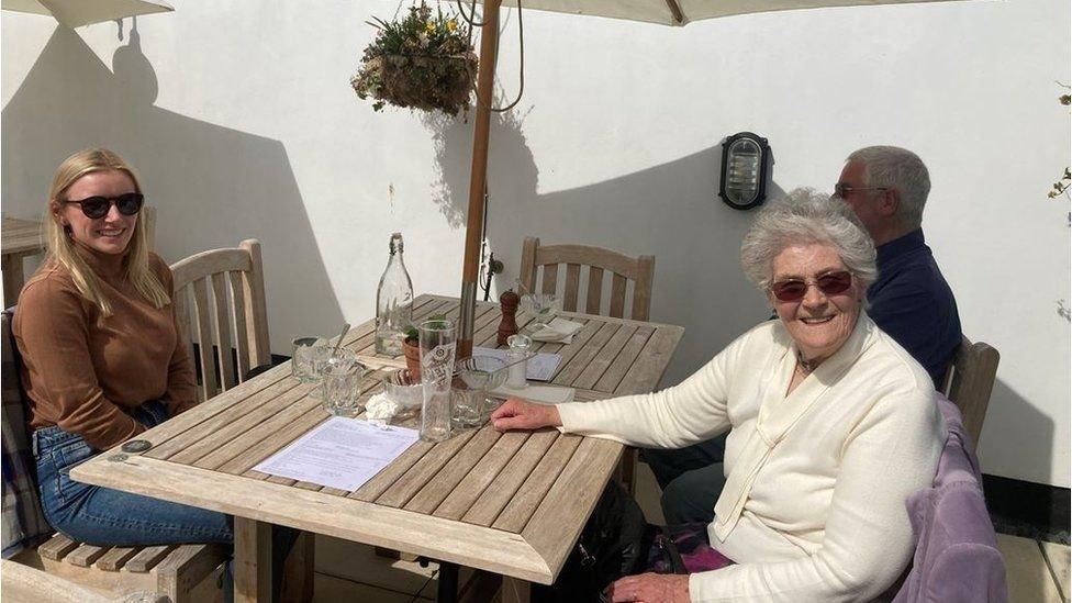 Three people enjoying a drink outside after outdoor hospitality opened in Wales on April 26