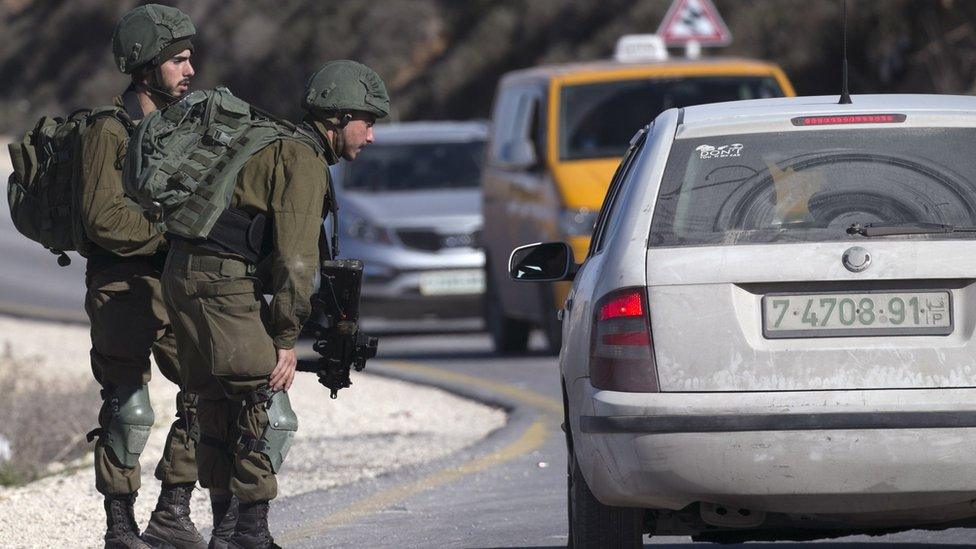 Israeli soldiers speak to a Palestinian driver at a checkpoint near the West Bank city of Nablus on 11 January 2018