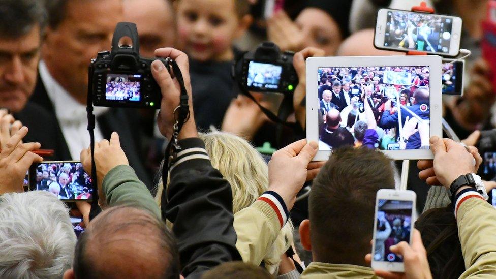 People raise their mobiles, tablets and cameras as Pope Francis arrives for his weekly general audience at the Paul VI audience Hall on 7 December 2016 at the Vatican