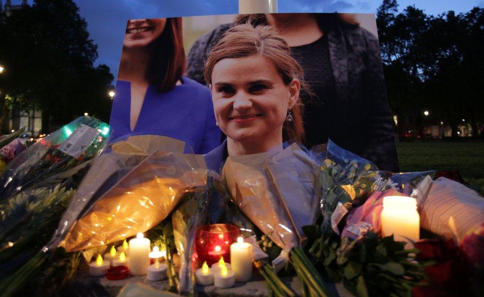 Floral tributes and candles are placed by a picture of Labour MP Jo Cox at a vigil in Parliament square in London