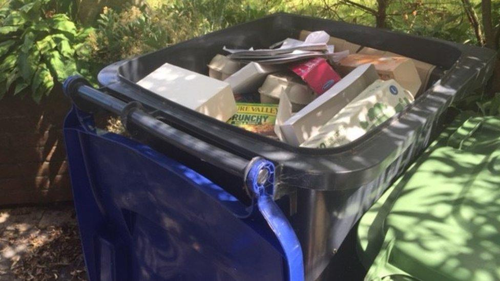 Wheeled rubbish bin filled with paper and card