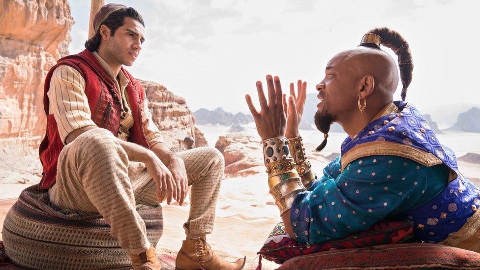 Aladdin-and-the-Genie-sit-on-the-ground-talking.