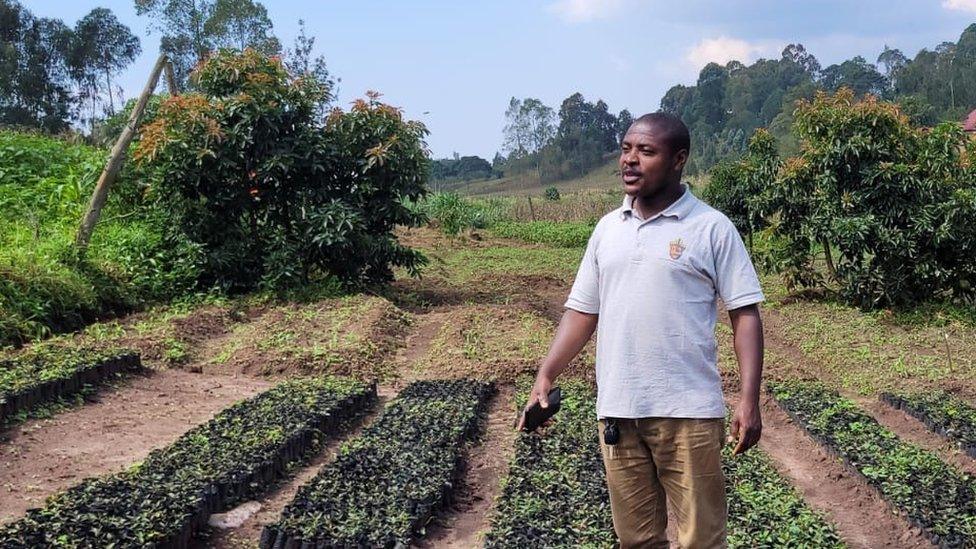 A Tanzanian farmer stands in front of farmland