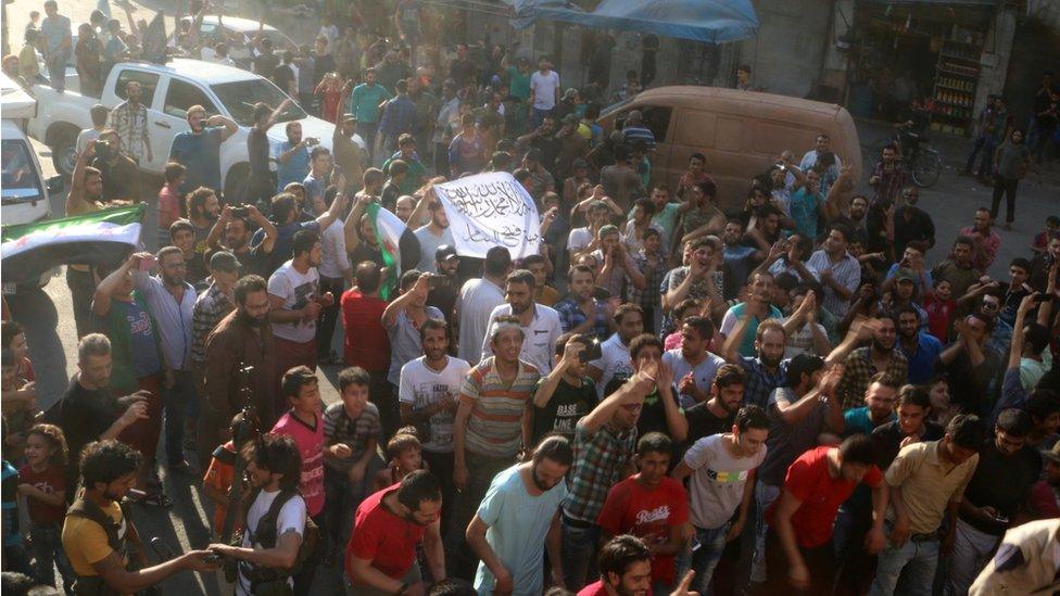 People carry a Free Syrian Army flag and a Jabhat Fatah al-Sham flag as they celebrate