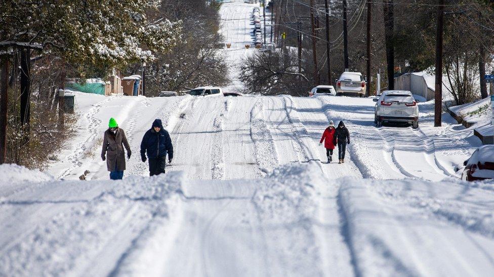 Pedestrians walk on an icy road on February 15, 2021 in East Austin, Texas.