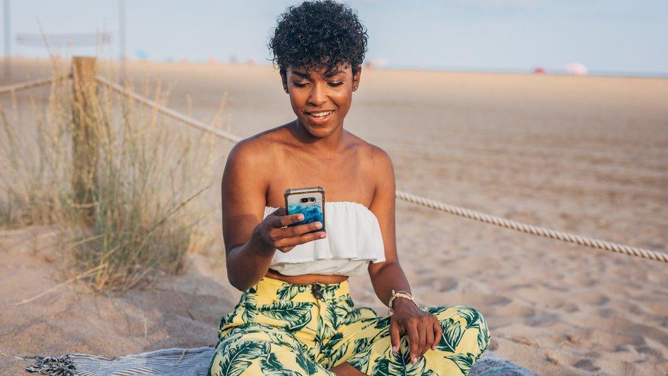 A woman on her phone on the beach