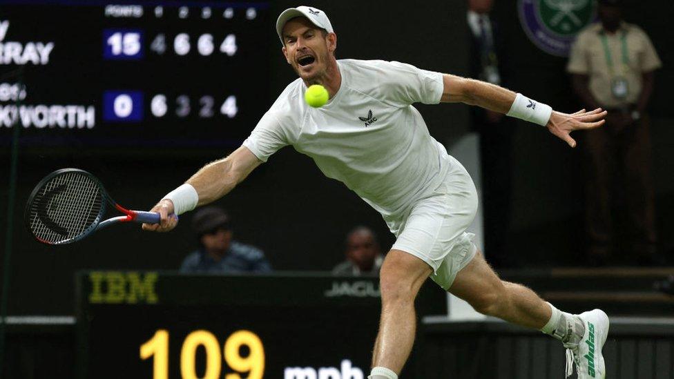 still shows andy murray launching towards a tennis ball with his racket raised