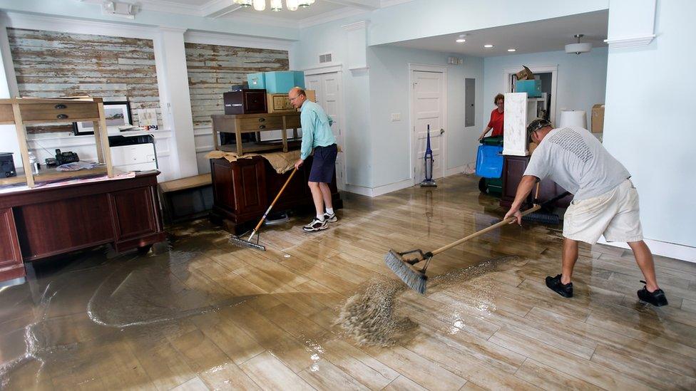 Shawn Stephenson, left, and Marshall Dimick clear water from a real estate office that was flooded by Hurricane Hermine Friday, 2 September 2016, in Cedar Key, Florida.