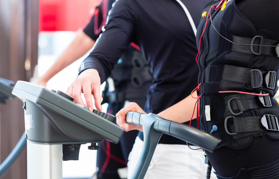Coach giving training to woman in electro stimulator suit