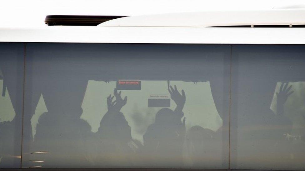 Migrants gestures on a bus leaving for a reception centre, in Calais, on October 28, 2016, following a massive operation to clear the Jungle migrant camp (28 October 2016)