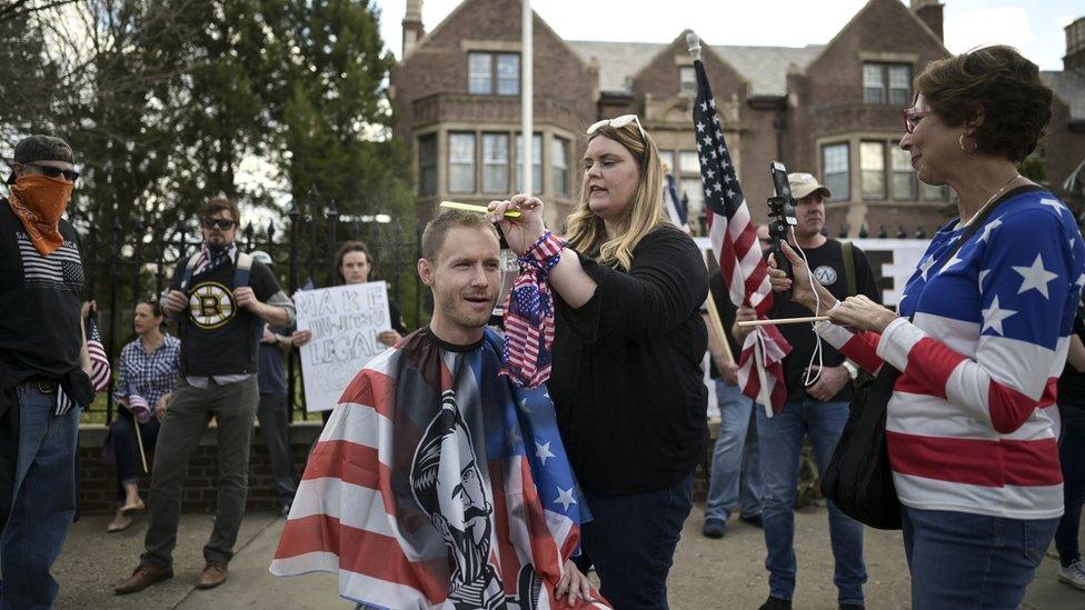 A hair stylist cuts the hair of a man, outside the Governor's Mansion in St Paul to protest the lockdown