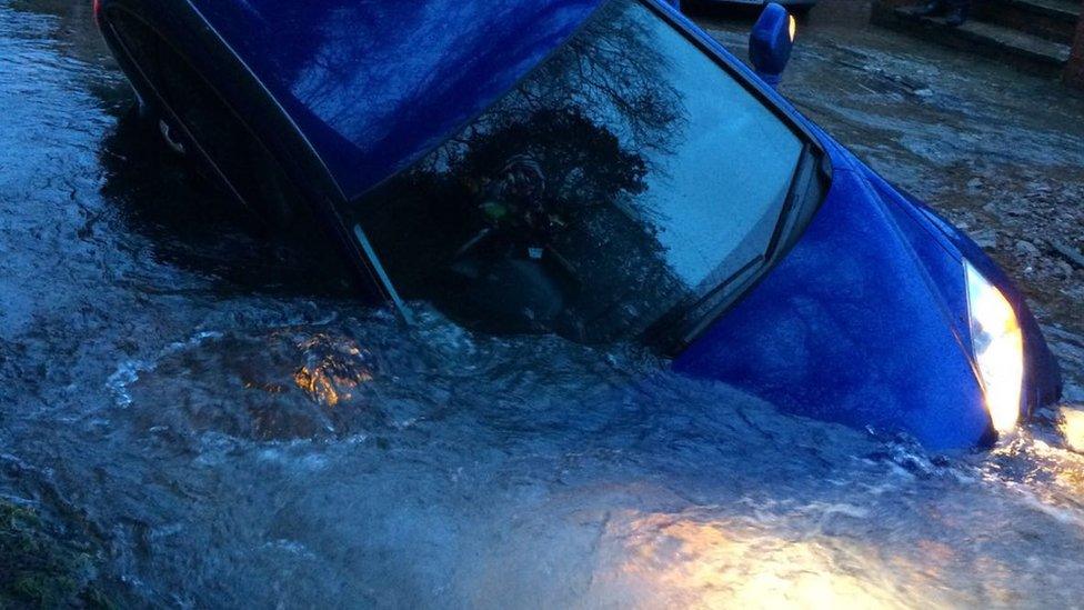 Car in a sinkhole created by a burst water main