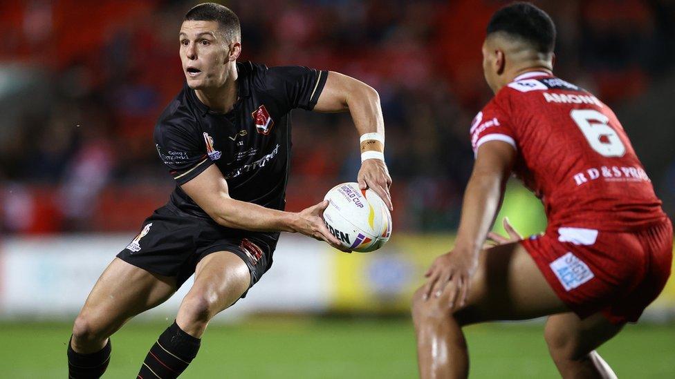 Josh Ralph of Wales looks to pass as Talatau Amone of Tonga closes in