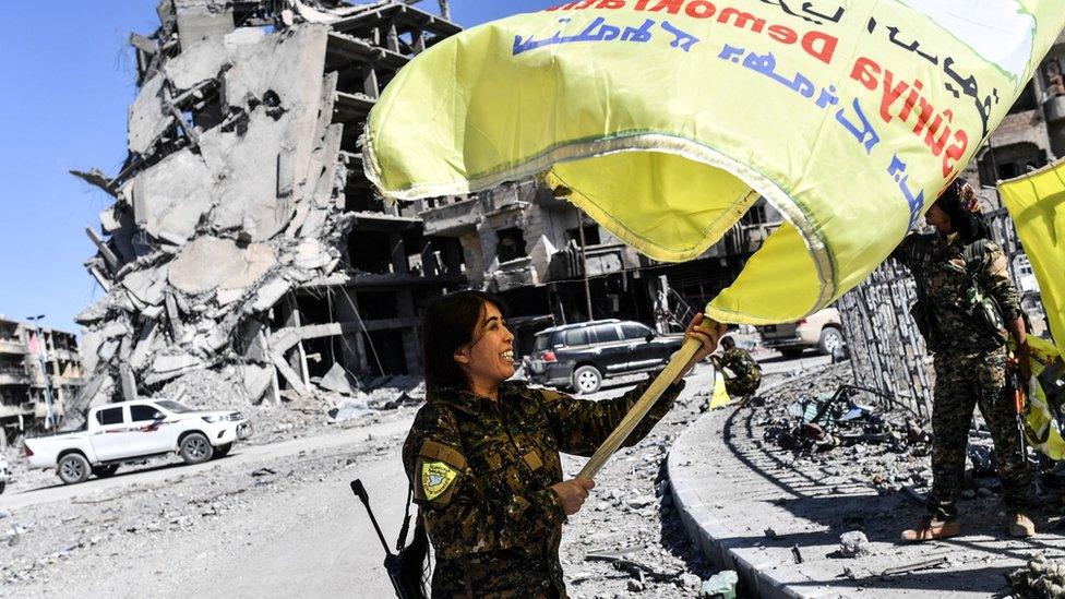 Rojda Felat, a Syrian Democratic Forces (SDF) commander, waves her group's flag in central Raqqa on 17 October 2017