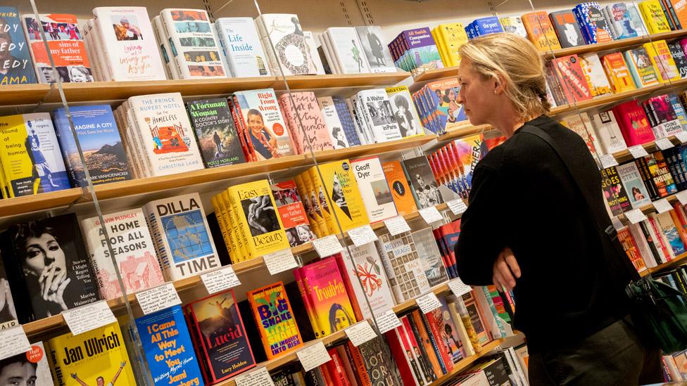 A woman looking at book displays in Waterstones, Piccadilly, London