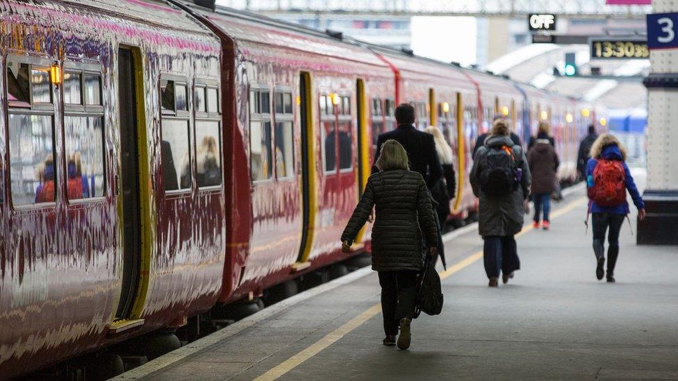 People walking along a train platform