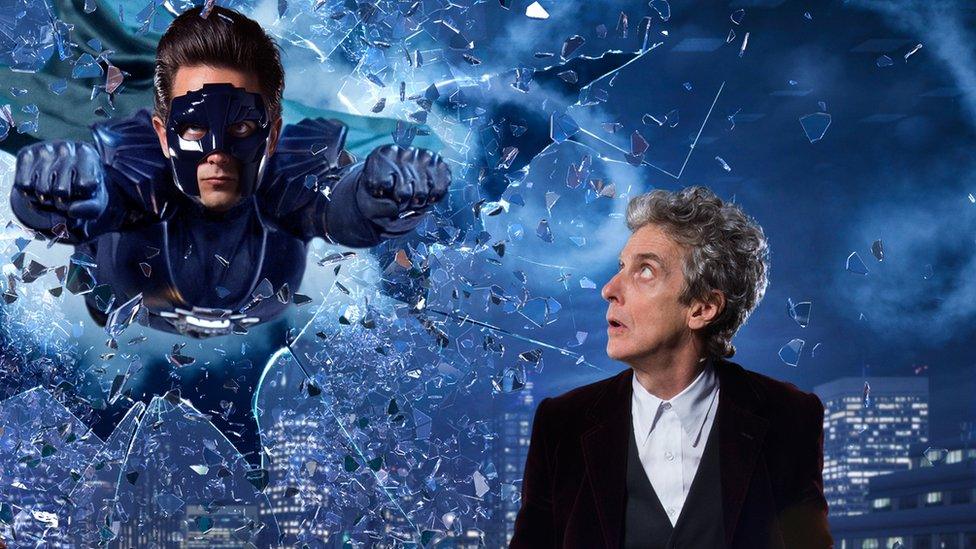 Peter Capaldi stood next to a masked super hero smashing through glass