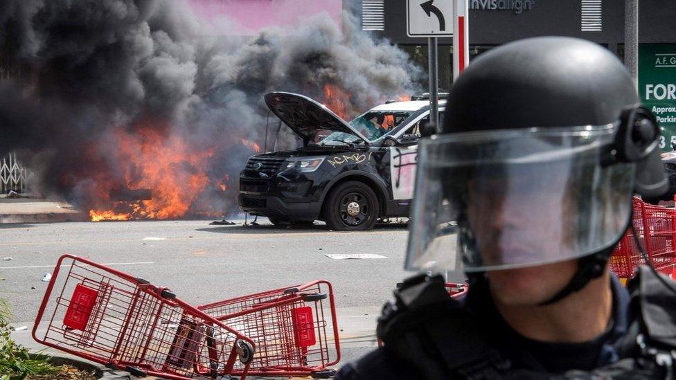 Police vehicles burn after being set on fire by demonstrators in the Fairfax District of Los Angeles as they protest the death of George Floyd, 30 May 2020