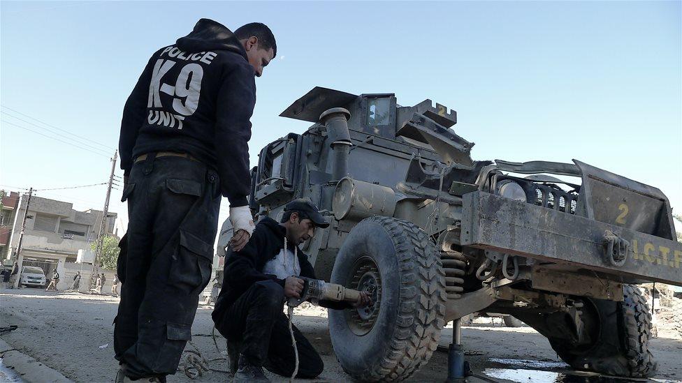 Troops attempt to fix a Humvee damaged in a car bomb in the Tahrir district of Mosul